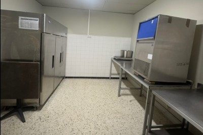 Bar rétro avec tabourets colorés, mur bleu, éclairage néon et jukebox dans un décor vintage.