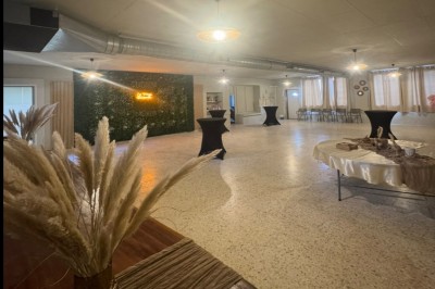 Bar rétro avec tabourets colorés, mur bleu, éclairage néon et jukebox dans un décor vintage.