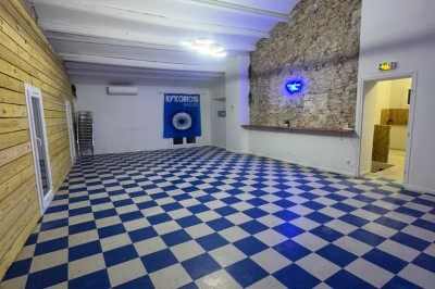 Bar rétro avec tabourets colorés, mur bleu, éclairage néon et jukebox dans un décor vintage.