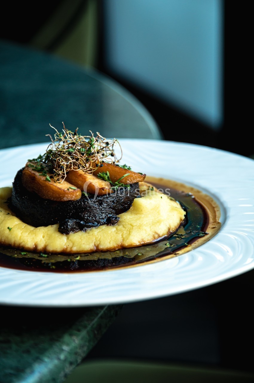 Assiette avec purée, champignons, tranches de légumes rôtis et garniture d'herbes sur une sauce brune.