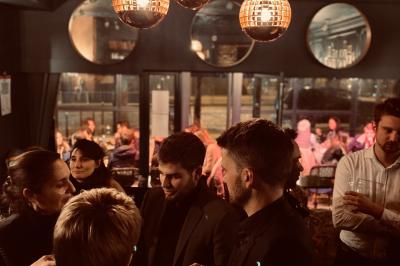 Salle de restaurant cosy avec fauteuils imprimés, éclairage tamisé et plafond décoré de motifs floraux.