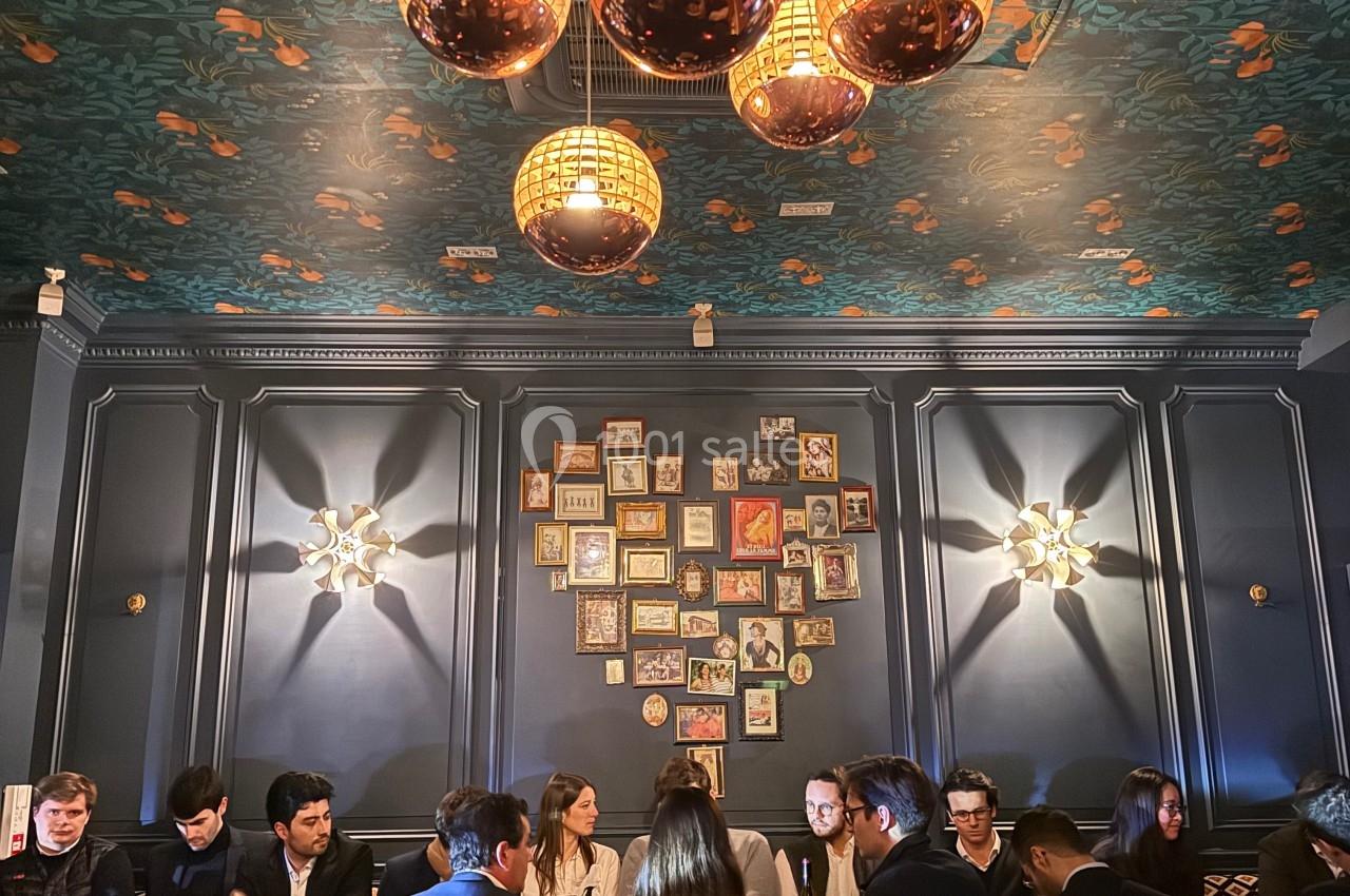 Groupe de personnes dînant dans un restaurant élégant avec un plafond décoré de motifs floraux et des luminaires suspendus.
