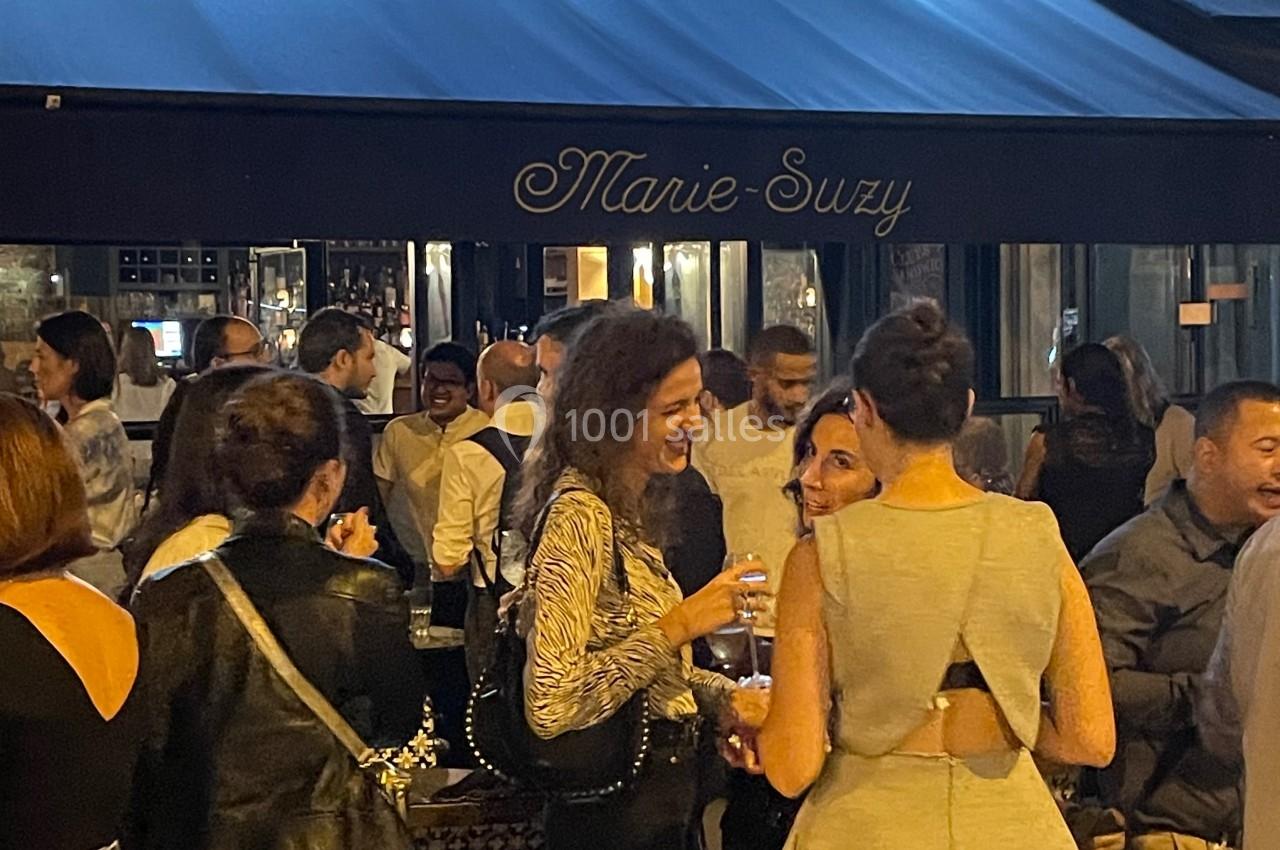 Groupe de personnes discutant et partageant un moment convivial devant un café en soirée.