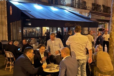 Salle de restaurant cosy avec fauteuils imprimés, éclairage tamisé et plafond décoré de motifs floraux.