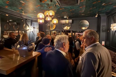 Salle de restaurant cosy avec fauteuils imprimés, éclairage tamisé et plafond décoré de motifs floraux.