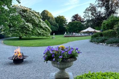Groupe de personnes assises en extérieur lors d'une cérémonie, entourées d'arbres et de fleurs sous un ciel partiellement…