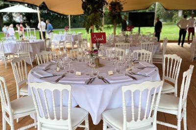 Dîner en plein air sous des guirlandes lumineuses, avec des invités assis autour de tables éclairées au crépuscule.
