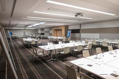 Trois distributeurs de savon fixés sur un mur de douche sombre, avec un éclairage jaune en reflet.