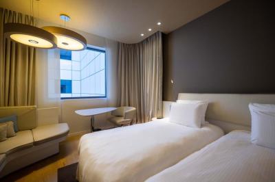 Trois distributeurs de savon fixés sur un mur de douche sombre, avec un éclairage jaune en reflet.