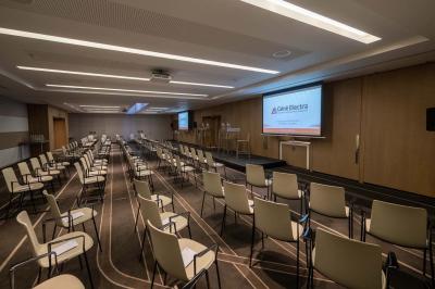 Trois distributeurs de savon fixés sur un mur de douche sombre, avec un éclairage jaune en reflet.