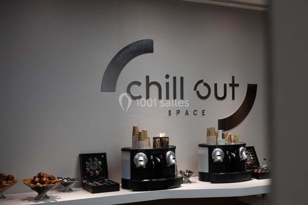 Deux machines à café avec tasses et condiments sur un comptoir, devant un mur avec l'inscription ’chill out space’.