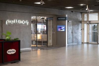 Trois distributeurs de savon fixés sur un mur de douche sombre, avec un éclairage jaune en reflet.