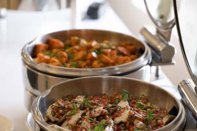Trois distributeurs de savon fixés sur un mur de douche sombre, avec un éclairage jaune en reflet.