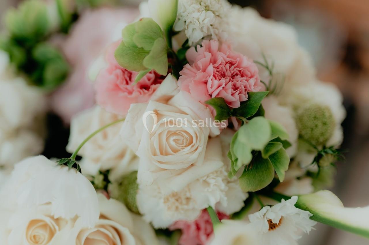 Bouquet de fleurs composé de roses blanches, œillets roses et feuillage vert, capturé en gros plan.