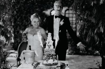 Un couple souriant marche main dans la main au milieu d'invités applaudissant lors d'une cérémonie en plein air.