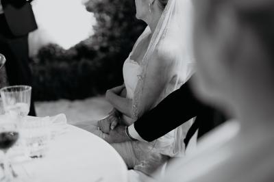 Un couple souriant marche main dans la main au milieu d'invités applaudissant lors d'une cérémonie en plein air.