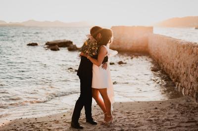 Un couple souriant marche main dans la main au milieu d'invités applaudissant lors d'une cérémonie en plein air.