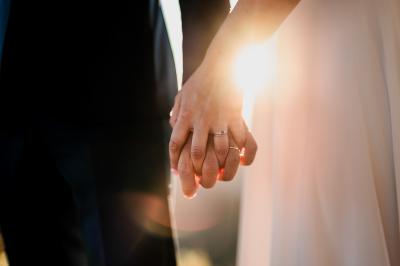 Un couple souriant marche main dans la main au milieu d'invités applaudissant lors d'une cérémonie en plein air.