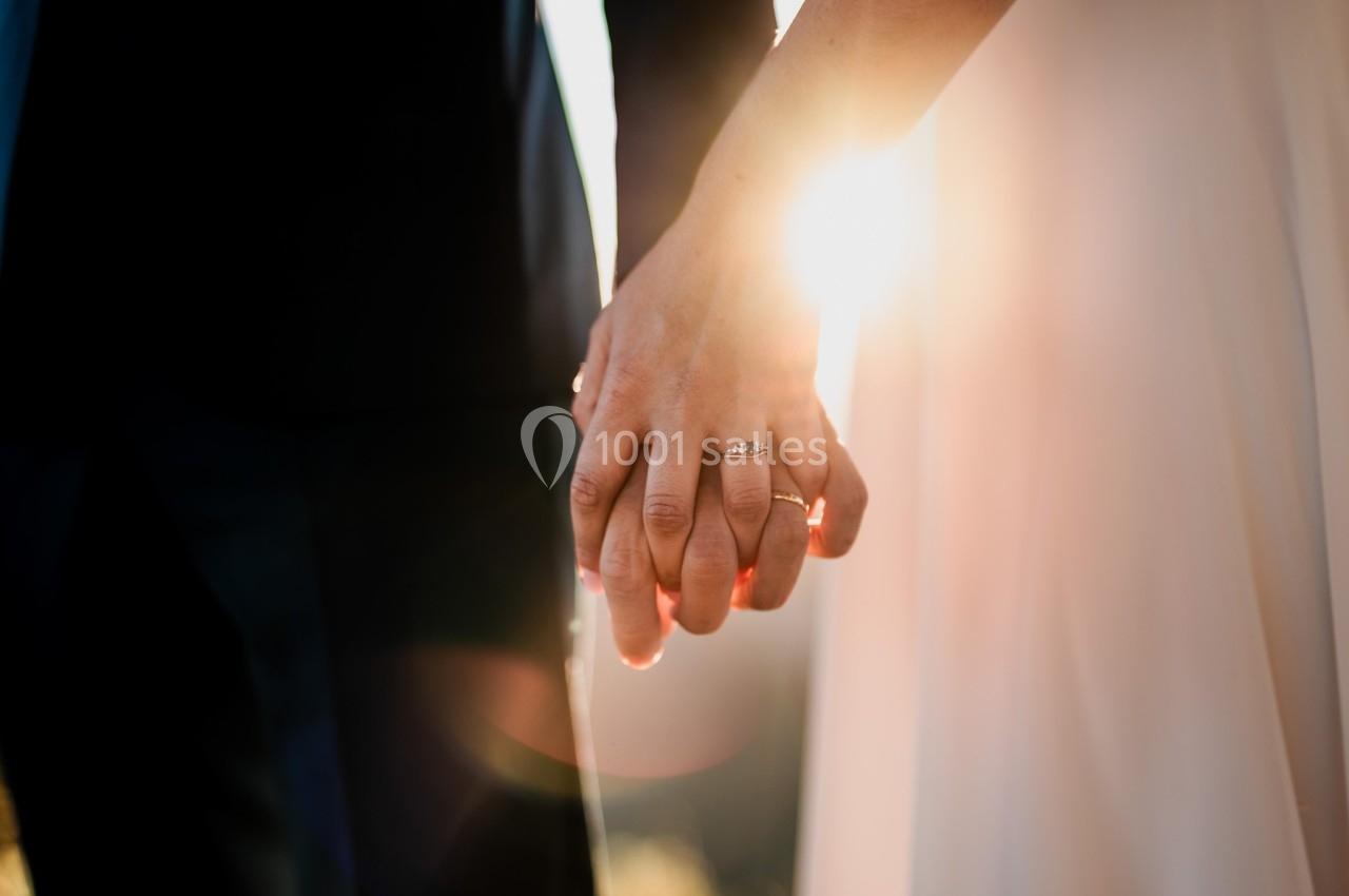 Deux personnes se tenant la main, avec une lumière du soleil traversant entre leurs doigts.