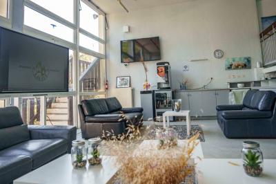 Deux lits simples avec couvre-lits bleus, une lampe de chevet, un bureau et un lavabo dans une chambre lumineuse.