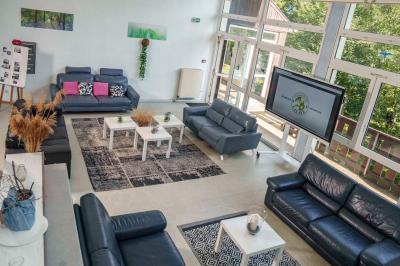 Deux lits simples avec couvre-lits bleus, une lampe de chevet, un bureau et un lavabo dans une chambre lumineuse.