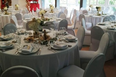 Deux lits simples avec couvre-lits bleus, une lampe de chevet, un bureau et un lavabo dans une chambre lumineuse.