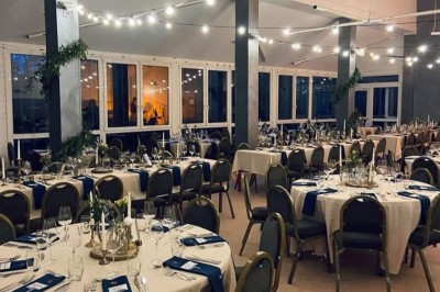 Deux lits simples avec couvre-lits bleus, une lampe de chevet, un bureau et un lavabo dans une chambre lumineuse.