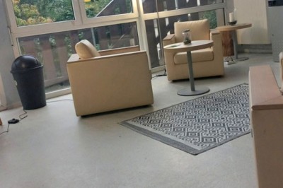 Deux lits simples avec couvre-lits bleus, une lampe de chevet, un bureau et un lavabo dans une chambre lumineuse.