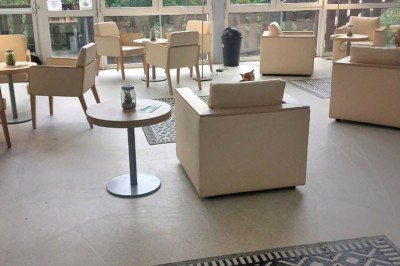 Deux lits simples avec couvre-lits bleus, une lampe de chevet, un bureau et un lavabo dans une chambre lumineuse.