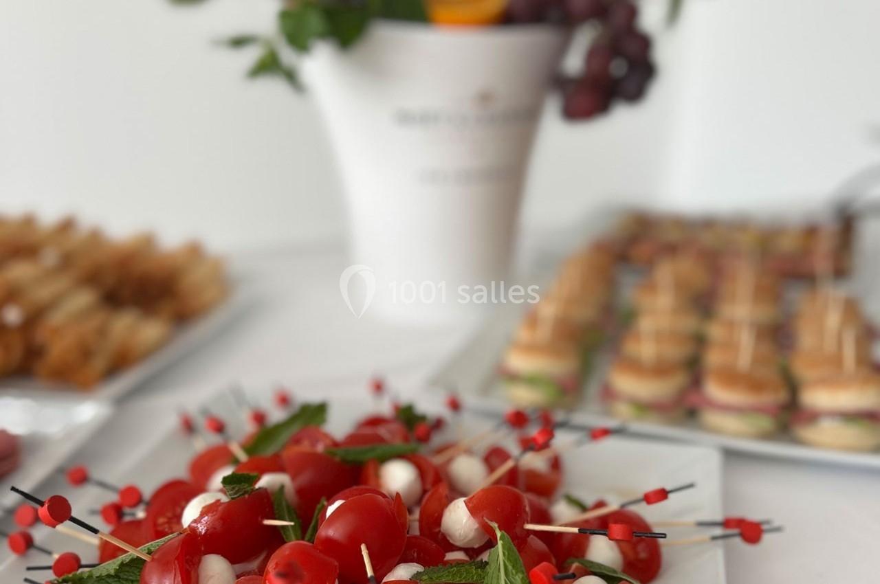 Brochettes apéritives avec tomates cerises, mozzarella et menthe, disposées sur une table avec d'autres amuse-bouches.
