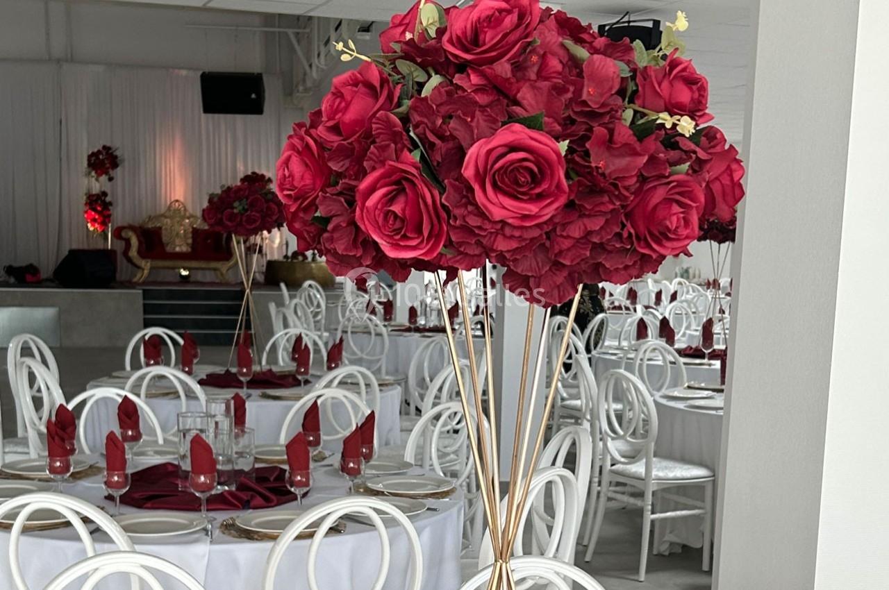 Centre de table composé de roses rouges et d'hortensias, placé dans une salle de réception élégamment décorée.