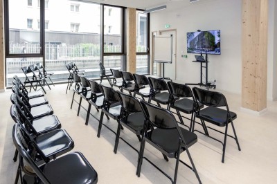 Façade d'un immeuble moderne en bois et verre avec des fenêtres alignées, situé dans un environnement urbain.