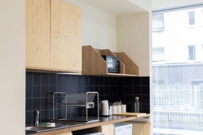 Façade d'un immeuble moderne en bois et verre avec des fenêtres alignées, situé dans un environnement urbain.