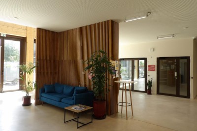 Façade d'un immeuble moderne en bois et verre avec des fenêtres alignées, situé dans un environnement urbain.