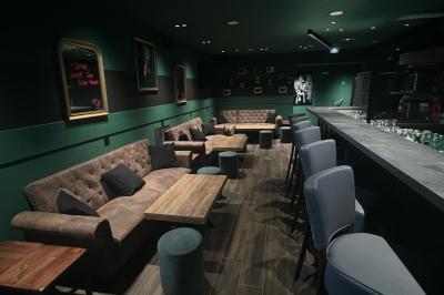 Chemin de gravier bordé de végétation, menant à un bâtiment moderne sous un ciel nuageux.