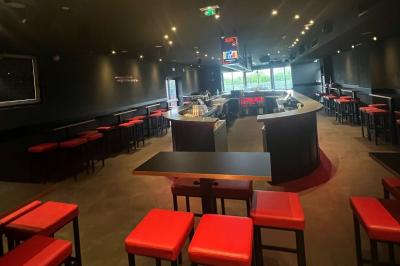 Chemin de gravier bordé de végétation, menant à un bâtiment moderne sous un ciel nuageux.