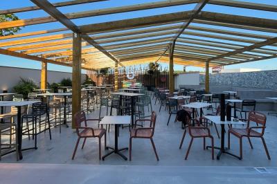 Chemin de gravier bordé de végétation, menant à un bâtiment moderne sous un ciel nuageux.