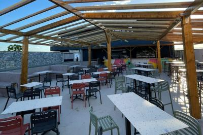 Chemin de gravier bordé de végétation, menant à un bâtiment moderne sous un ciel nuageux.