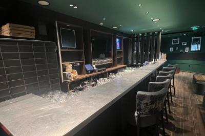 Chemin de gravier bordé de végétation, menant à un bâtiment moderne sous un ciel nuageux.