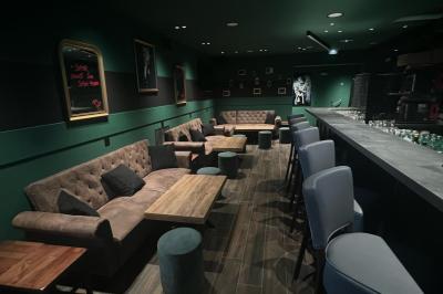 Terrain gravillonné entouré de végétation, avec un bâtiment moderne à droite et un ciel nuageux en arrière-plan.