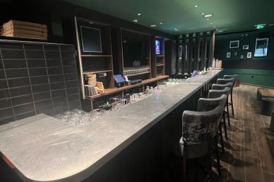 Terrain gravillonné entouré de végétation, avec un bâtiment moderne à droite et un ciel nuageux en arrière-plan.