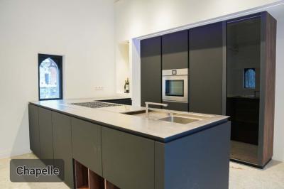 Des personnes discutent debout dans un espace extérieur, entourées de verdure et de mobilier de jardin.