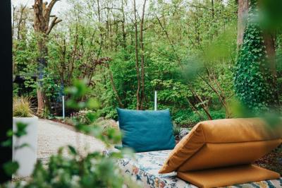 Des personnes discutent debout dans un espace extérieur, entourées de verdure et de mobilier de jardin.