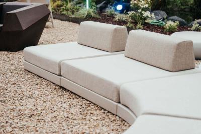 Des personnes discutent debout dans un espace extérieur, entourées de verdure et de mobilier de jardin.