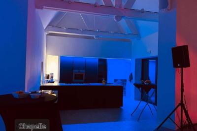 Des personnes discutent debout dans un espace extérieur, entourées de verdure et de mobilier de jardin.