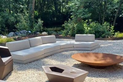 Des personnes discutent debout dans un espace extérieur, entourées de verdure et de mobilier de jardin.