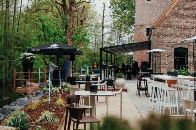 Des personnes discutent debout dans un espace extérieur, entourées de verdure et de mobilier de jardin.