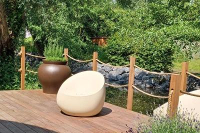 Des personnes discutent debout dans un espace extérieur, entourées de verdure et de mobilier de jardin.