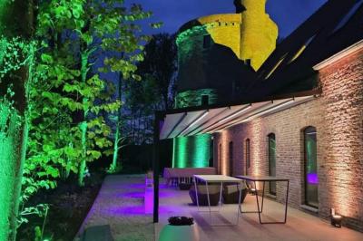 Des personnes discutent debout dans un espace extérieur, entourées de verdure et de mobilier de jardin.