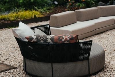 Des personnes discutent debout dans un espace extérieur, entourées de verdure et de mobilier de jardin.